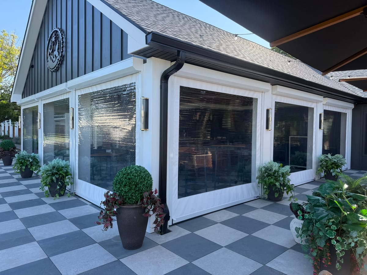 Clear-vinyl motorized screens enclosing a restaurant patio pavilion, screens closed