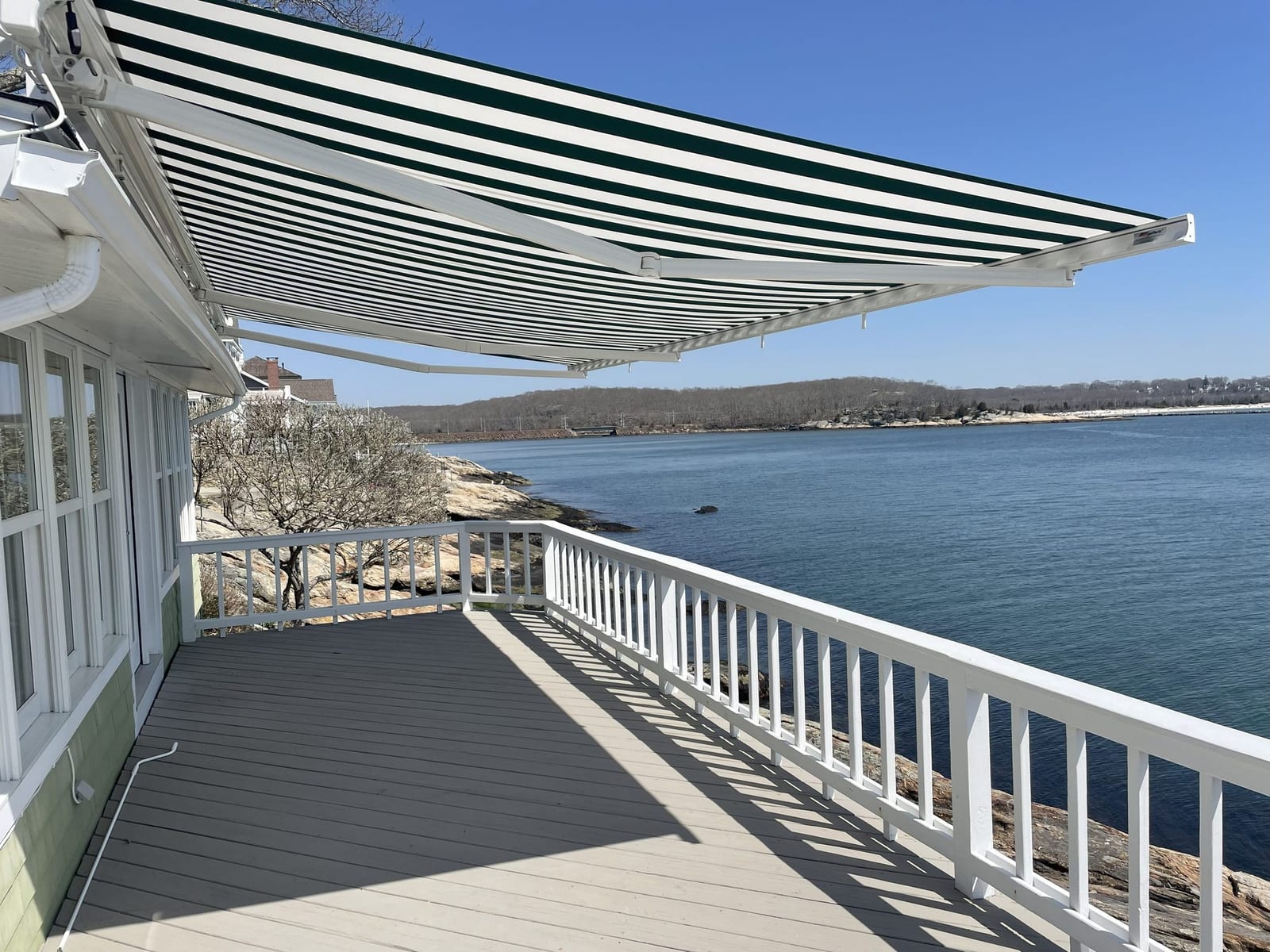 Green and white striped retractable awning on a waterfront deck
