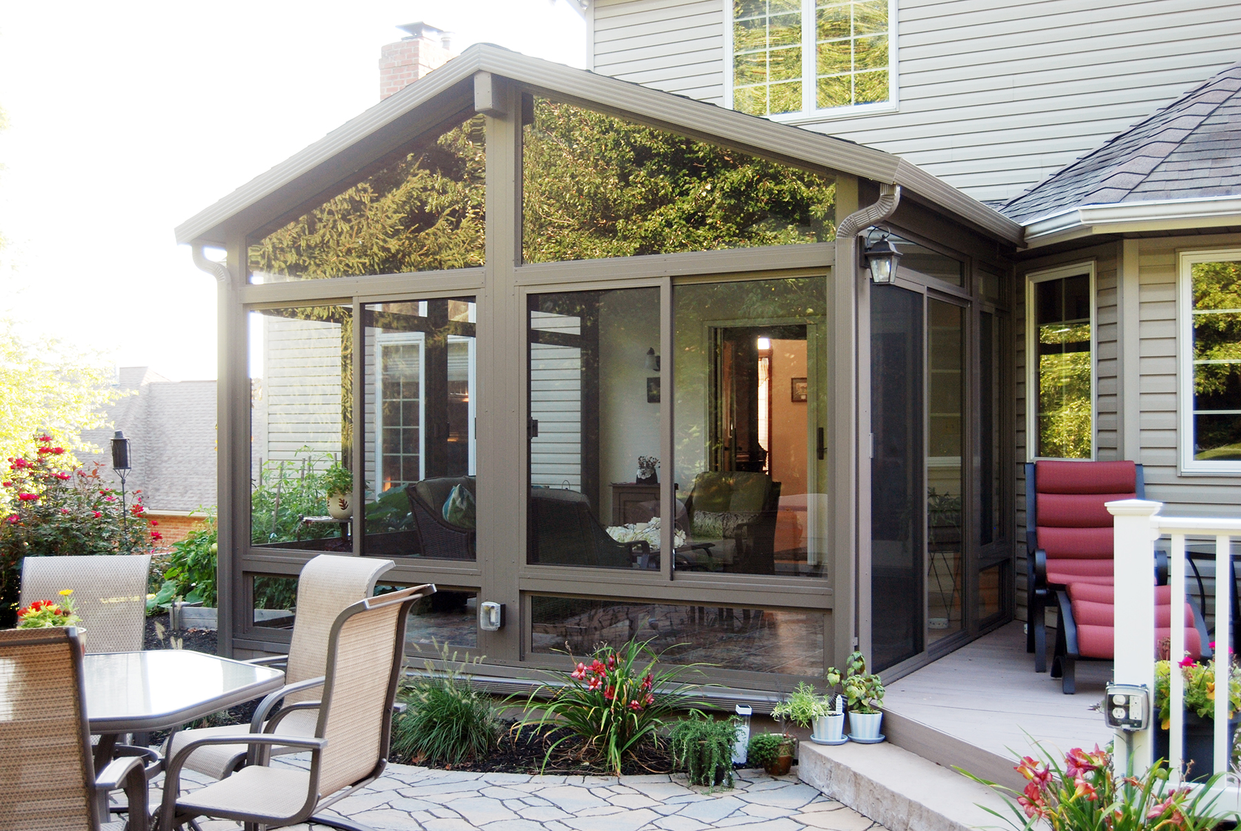 Custom gable sunroom with dark frame on patio with outdoor dining